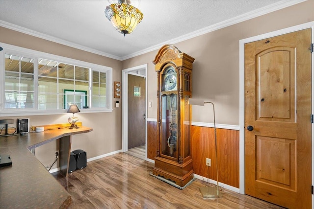 foyer with wood finished floors, a wainscoted wall, baseboards, and ornamental molding