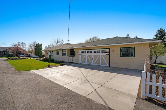 ranch-style home with concrete driveway, an attached garage, fence, and a front lawn