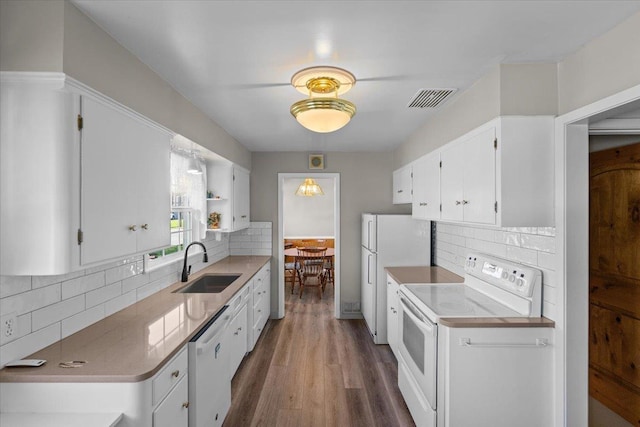 kitchen with backsplash, visible vents, a sink, white appliances, and white cabinetry