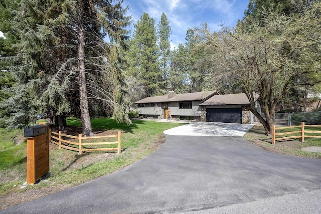 view of front facade with aphalt driveway, fence, a front lawn, roof with shingles, and a garage