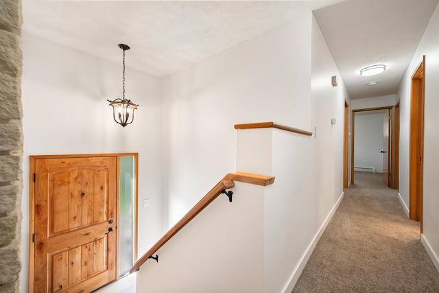 foyer with a baseboard heating unit, light carpet, baseboards, and a notable chandelier