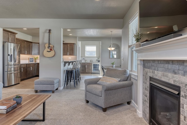 living room with a fireplace, beverage cooler, and light colored carpet