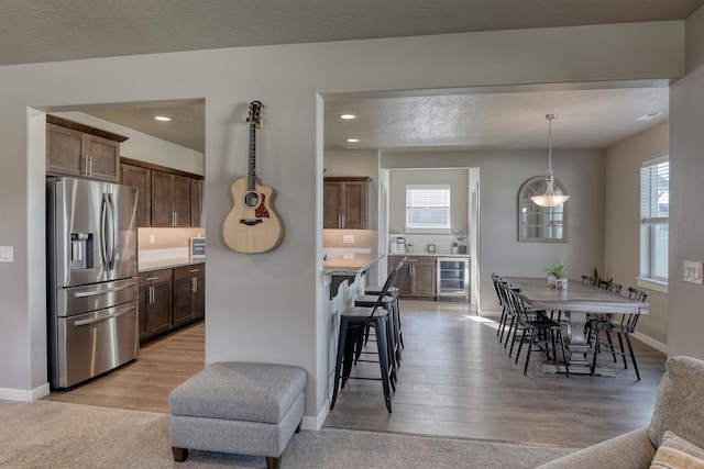 kitchen featuring plenty of natural light, beverage cooler, light countertops, and stainless steel fridge