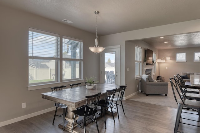 dining room featuring visible vents, baseboards, recessed lighting, wood finished floors, and a fireplace