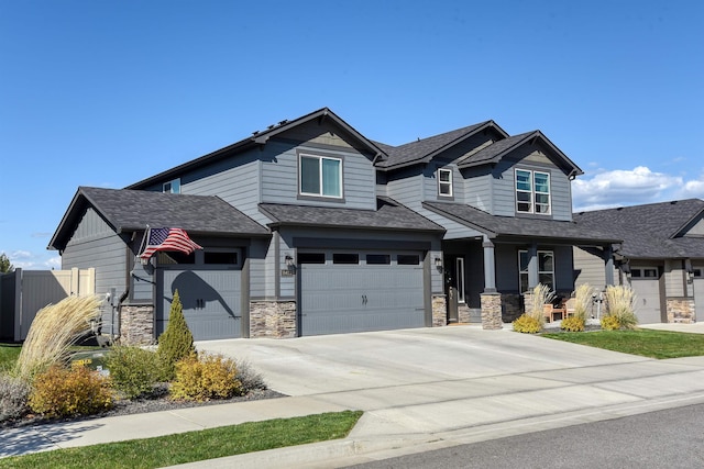 craftsman-style house with fence, concrete driveway, covered porch, stone siding, and a garage
