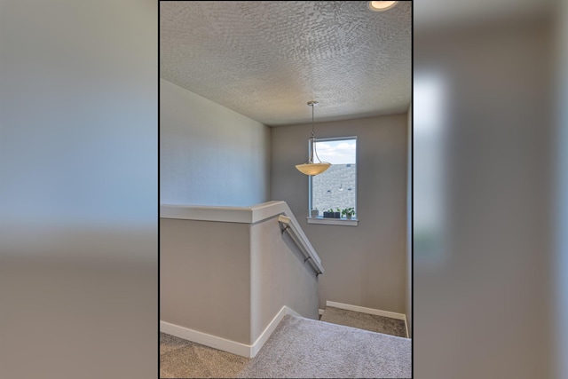 staircase with baseboards, a textured ceiling, and carpet