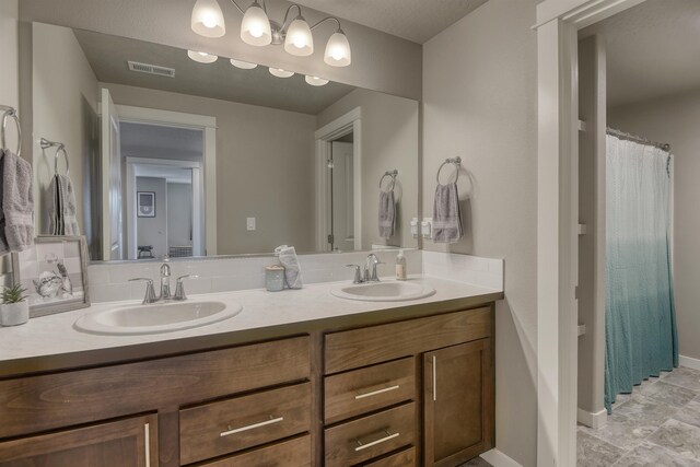 full bathroom with baseboards, a sink, visible vents, and double vanity