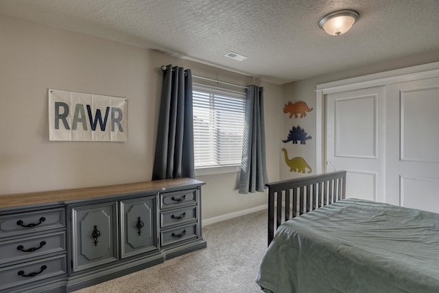 carpeted bedroom featuring baseboards, visible vents, a textured ceiling, and a closet