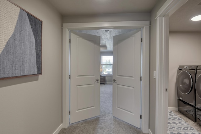 hallway with baseboards, washer and clothes dryer, and carpet