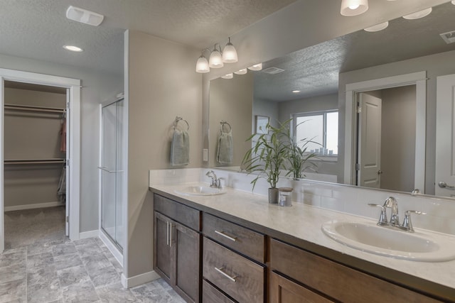 full bath with visible vents, a shower stall, a sink, and a textured ceiling