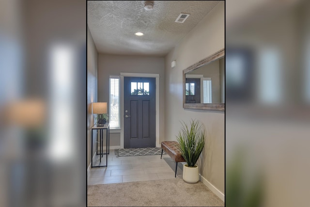 doorway to outside featuring light carpet, a textured ceiling, light tile patterned flooring, baseboards, and visible vents