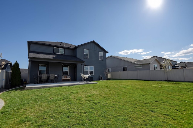 back of house with fence, board and batten siding, a yard, and a patio