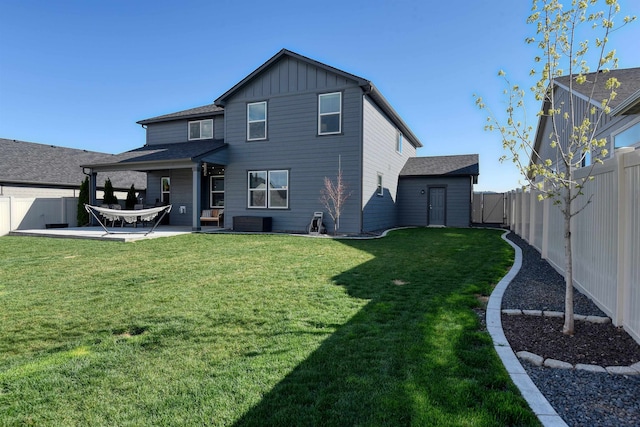 rear view of property featuring board and batten siding, a patio area, a fenced backyard, and a yard