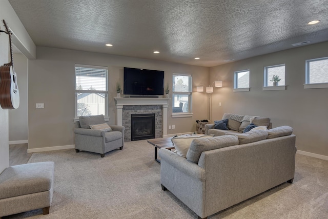living area with visible vents, baseboards, a fireplace, a textured ceiling, and light colored carpet