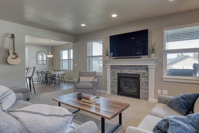 living area with baseboards, a stone fireplace, recessed lighting, and a textured ceiling