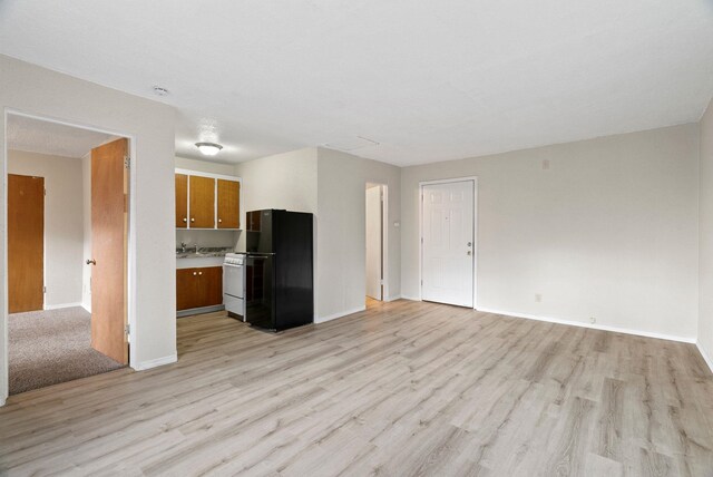 901 S Lincoln St, Spokane, WA 99204 - unfurnished living room with baseboards, light wood-style floors, and a sink
