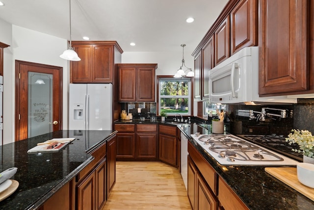kitchen with backsplash, a sink, white appliances, pendant lighting, and light wood-style flooring