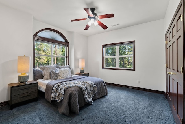 bedroom featuring baseboards, dark colored carpet, multiple windows, and visible vents