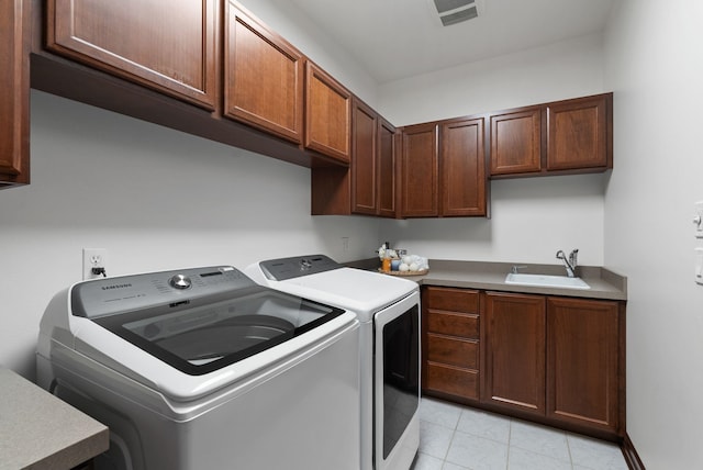 laundry area with visible vents, light tile patterned floors, a sink, washer and dryer, and cabinet space