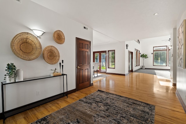 hallway with baseboards, wood finished floors, visible vents, and recessed lighting