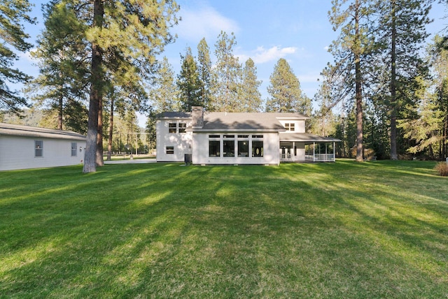rear view of property featuring a lawn and a chimney