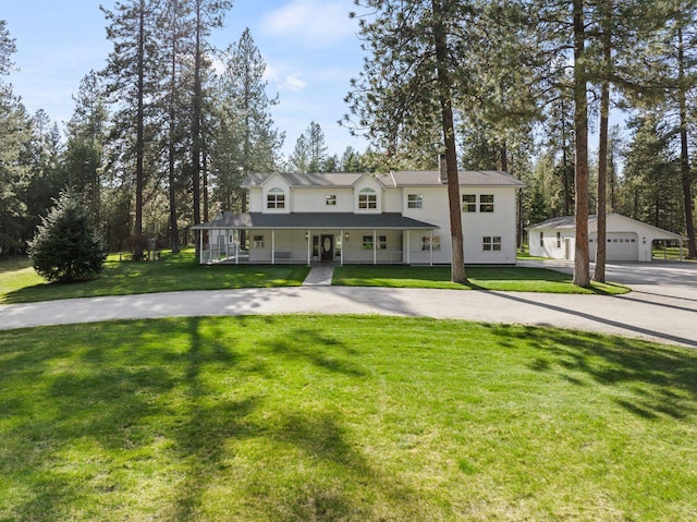view of front of house with an outdoor structure, a porch, a detached garage, and a front yard