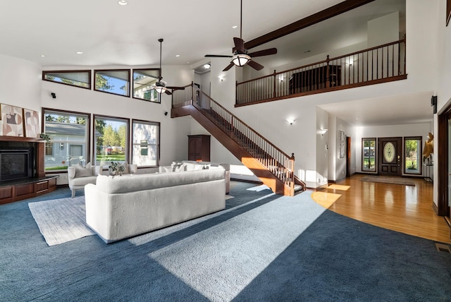 living room with a ceiling fan, a high ceiling, carpet, and stairway