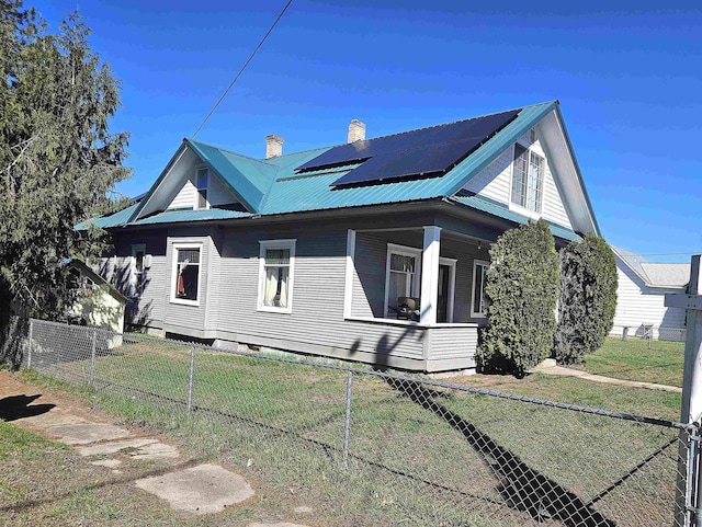 303 N Vernon St, Deer Park, WA 99006 - view of side of property featuring a porch, metal roof, fence private yard, a yard, and roof mounted solar panels