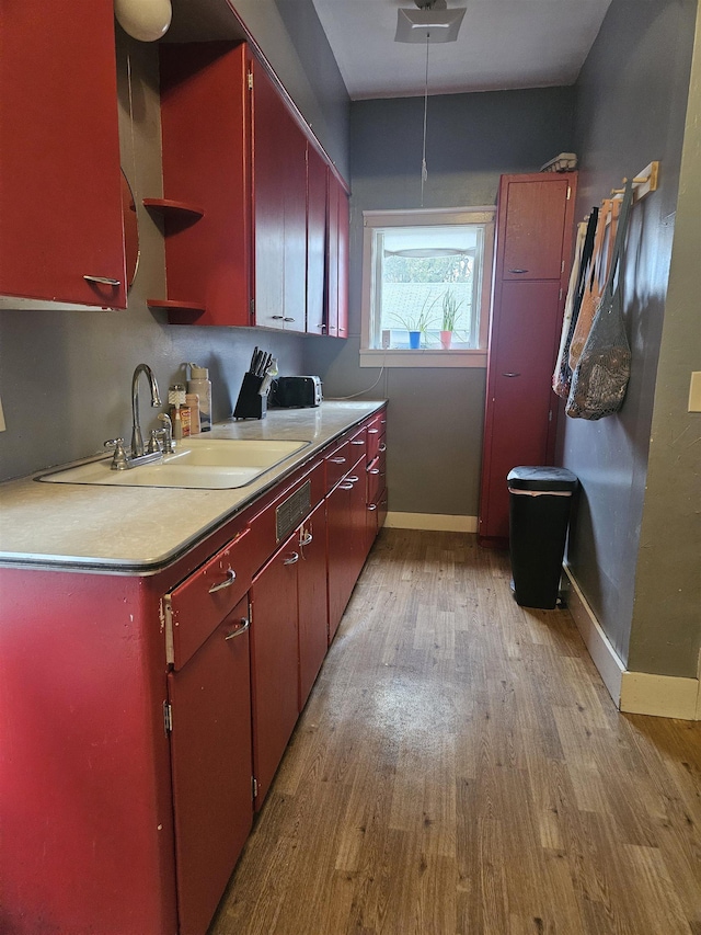 303 N Vernon St, Deer Park, WA 99006 - kitchen featuring red cabinets, baseboards, a sink, and light wood finished floors