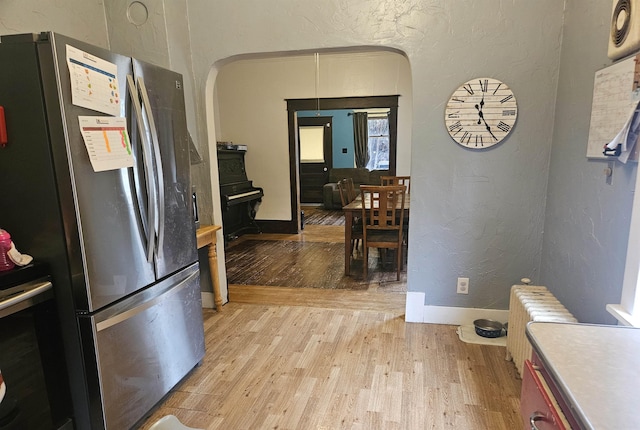 303 N Vernon St, Deer Park, WA 99006 - kitchen with arched walkways, a textured wall, light wood-type flooring, and freestanding refrigerator