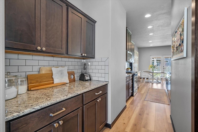 kitchen featuring tasteful backsplash, light wood-type flooring, appliances with stainless steel finishes, and dark brown cabinetry