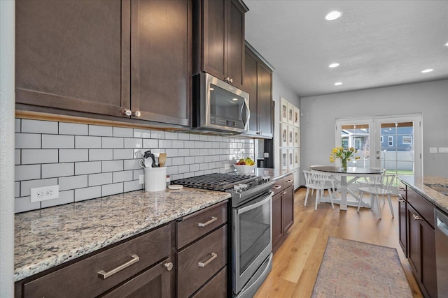 kitchen with recessed lighting, stainless steel appliances, dark brown cabinetry, decorative backsplash, and light wood-style flooring