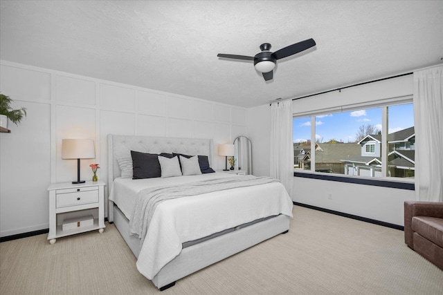 bedroom with a ceiling fan, baseboards, a textured ceiling, and light colored carpet
