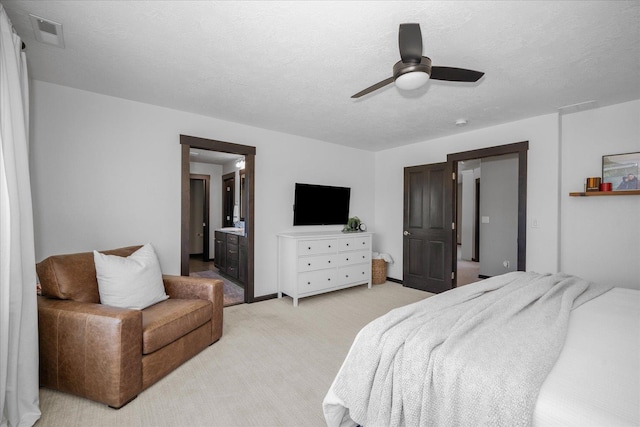 bedroom featuring a ceiling fan, a textured ceiling, light carpet, ensuite bath, and visible vents