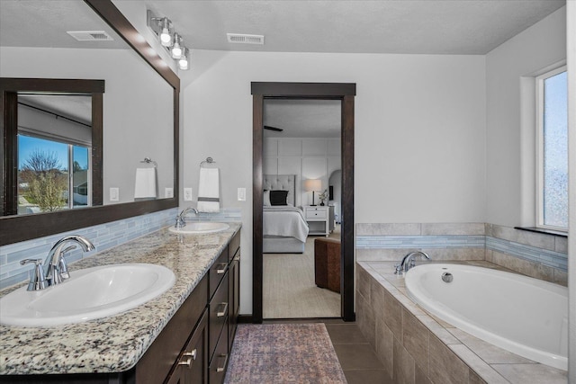 ensuite bathroom with a wealth of natural light, visible vents, a sink, and connected bathroom