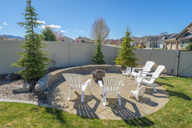 view of yard with a residential view, a patio area, a fenced backyard, and an outdoor fire pit