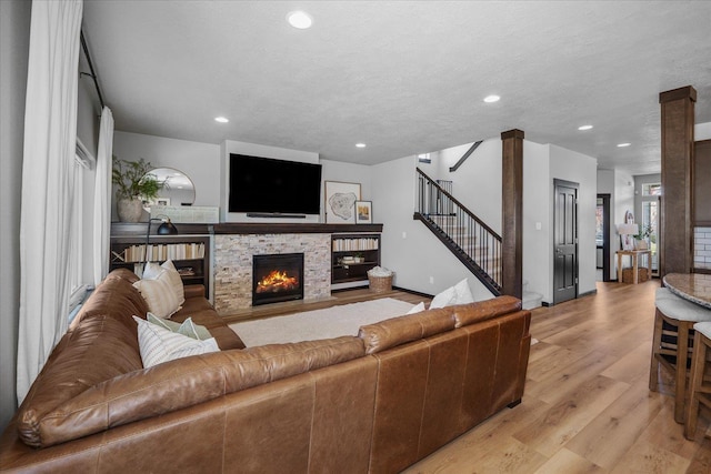 living room featuring recessed lighting, stairway, light wood-style flooring, and a stone fireplace