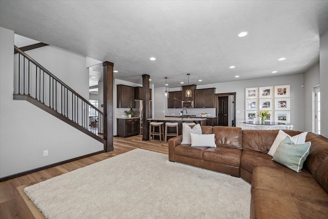 living room with baseboards, recessed lighting, stairs, and light wood-type flooring