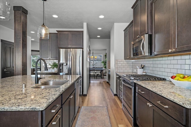 kitchen with light wood-style flooring, appliances with stainless steel finishes, dark brown cabinetry, and a sink