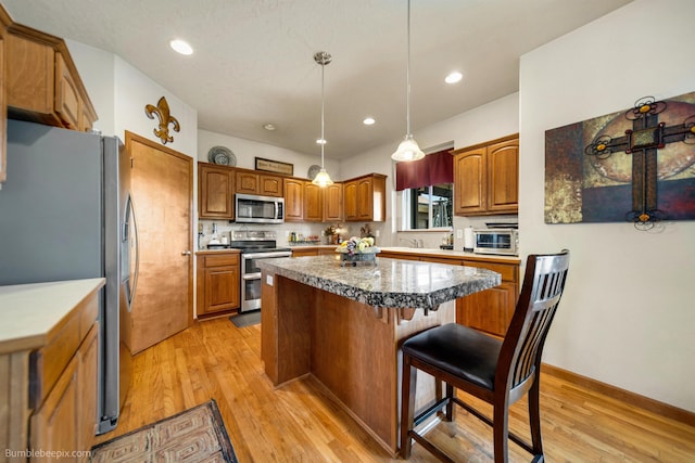 17202 E Morningside Ln, Greenacres, WA 99037 - kitchen featuring brown cabinetry, a breakfast bar, light wood-style flooring, appliances with stainless steel finishes, and a kitchen island