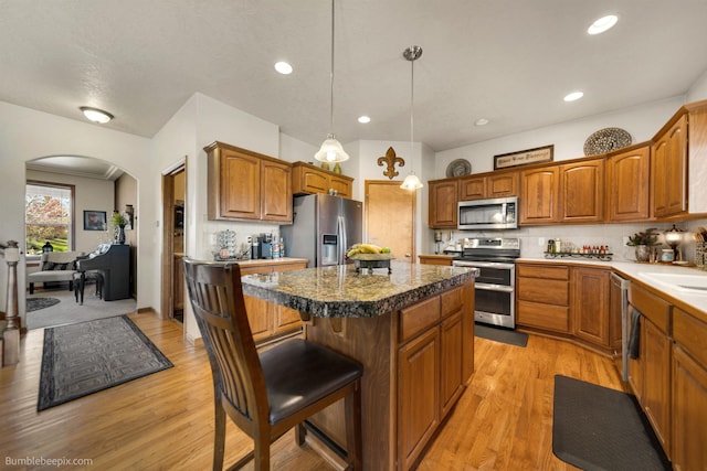 17202 E Morningside Ln, Greenacres, WA 99037 - kitchen featuring a center island, arched walkways, appliances with stainless steel finishes, and light wood-style flooring