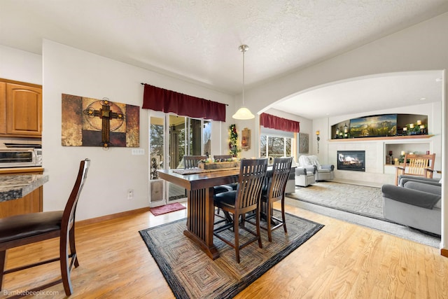 17202 E Morningside Ln, Greenacres, WA 99037 - dining room with light wood finished floors, arched walkways, baseboards, a fireplace, and a textured ceiling