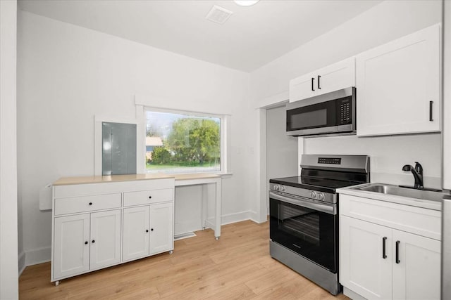 1873 E Marshall Ave, Spokane, WA 99207 - kitchen featuring light wood-style flooring, appliances with stainless steel finishes, white cabinetry, and a sink