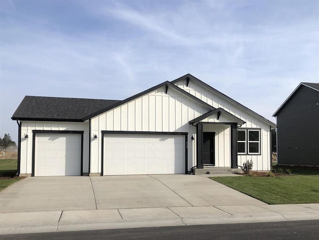 view of front of house with concrete driveway, board and batten siding, an attached garage, a front yard, and roof with shingles