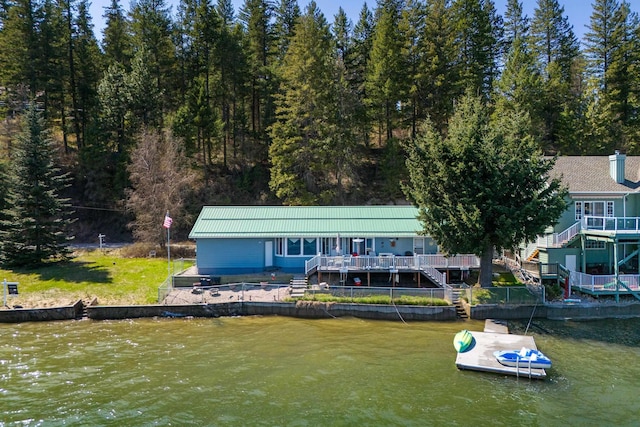 rear view of property with a forest view, a water view, and stairway