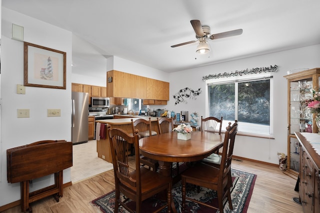 dining room with light wood-type flooring, a ceiling fan, and baseboards