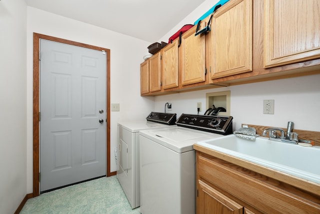 clothes washing area featuring a sink, baseboards, separate washer and dryer, cabinet space, and light floors