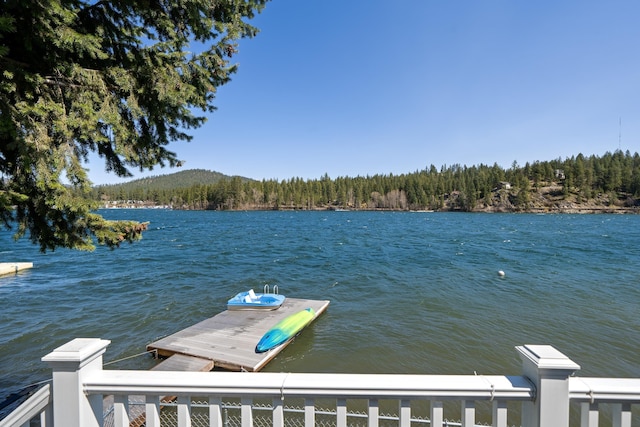 view of water feature with a floating dock and a wooded view