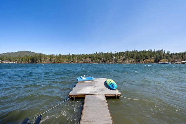 view of dock featuring a wooded view and a water view