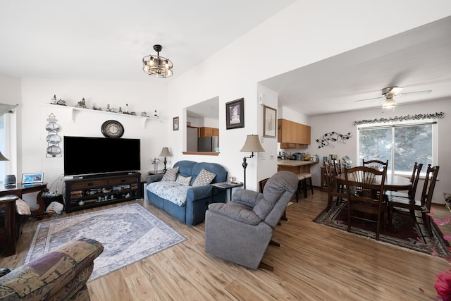 living area featuring light wood-style floors and ceiling fan with notable chandelier